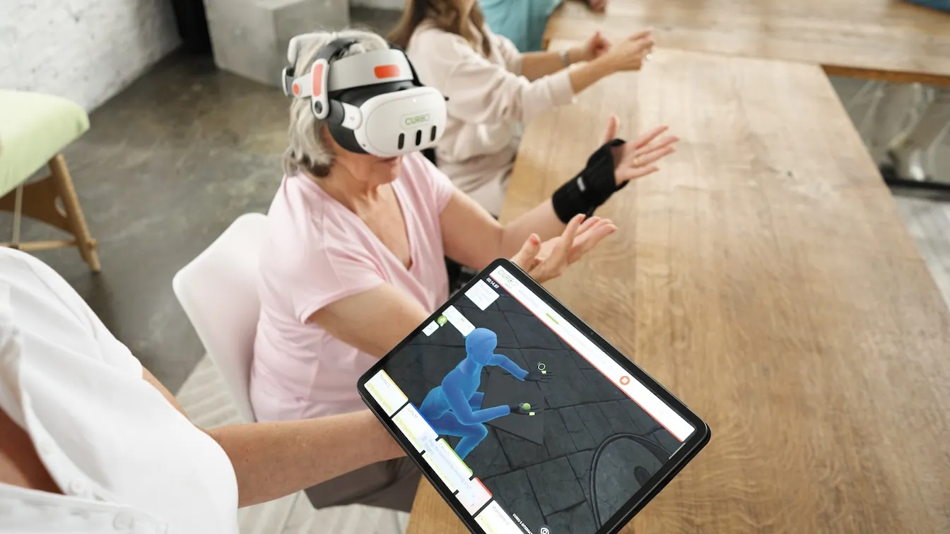 Paciente con visor de realidad virtual y férula en la mano; la tablet muestra su avatar en el entorno virtual